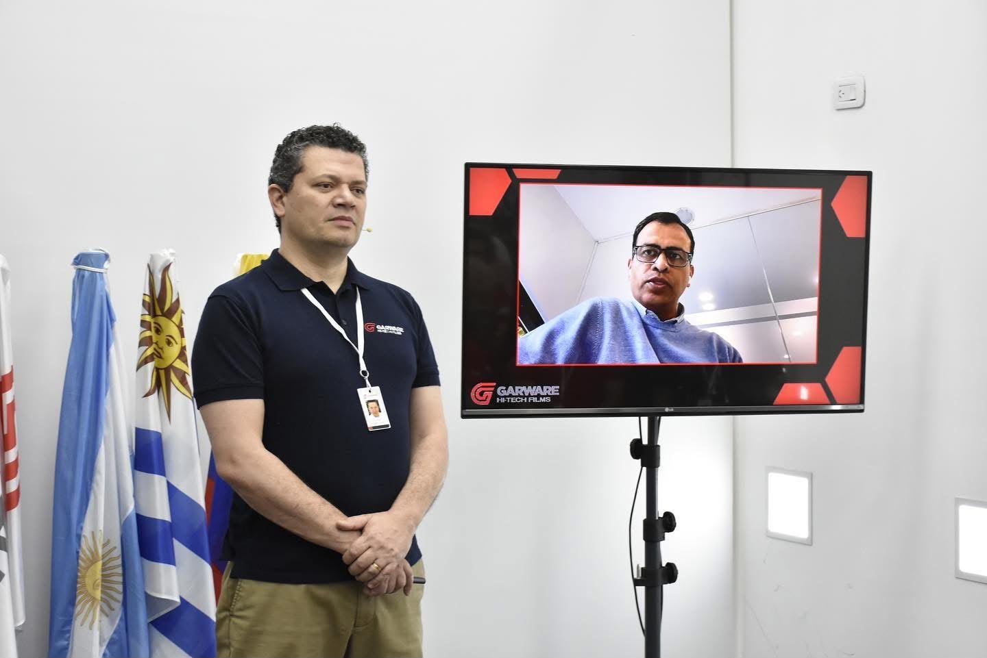 Participante presencial junto a una pantalla con un invitado remoto