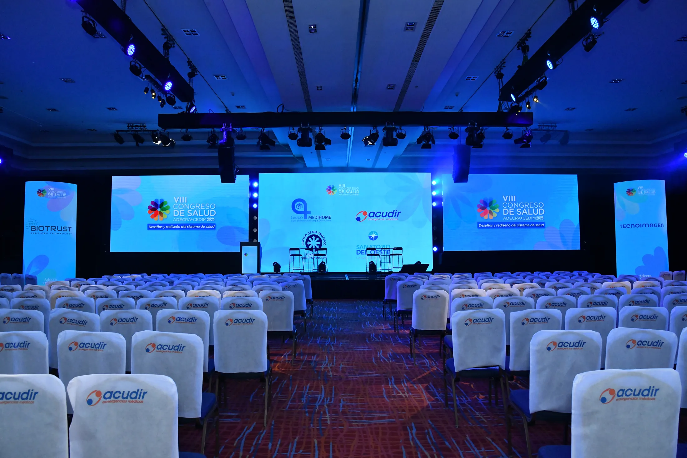 Escenario de congreso con múltiples pantallas y puesta audiovisual